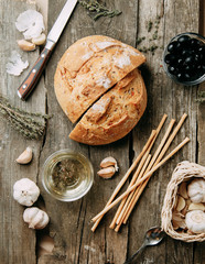 Baking on a wooden background. Fresh sliced white bread. Oil and olives with spices.