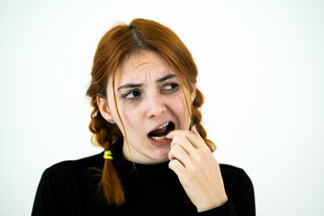 Youn woman with open mouth digging with her fingers for something stuck in teeth after eating.