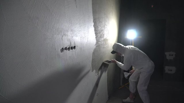Construction worker plastering and smoothing concrete wall with putty. Putty and leveling walls for subsequent painting. Worker making repair in room. Builder using plastering tool for finishing wall