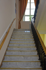 Old stone staircase with a handrail in a building without an elevator