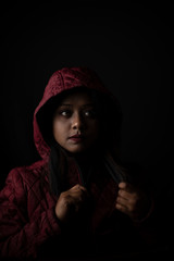 Fashion portrait of an young Indian Bengali brunette woman with maroon winter hoodie jacket in black copy space background. Indian lifestyle and fashion photography.