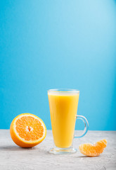 Glass of orange juice on a gray and blue background. Side view