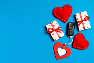 Top view of car key, gift boxes and toy hearts on colorful background. Saint Valentine's Day concept with copy space