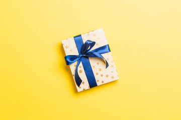 Top view Christmas present box with blue bow on yellow background with copy space