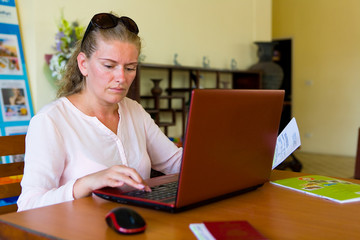 Cute natural blonde working on a laptop while sitting at a table.