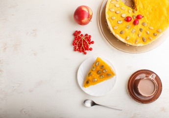 Traditional american sweet pumpkin pie decorated with hawthorn red berries and pumpkin seeds with cup of coffee on a white wooden background. top view.