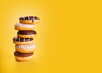 The pile of different types of donuts on yellow background. Sweet pastries of Fat Thursday....