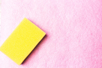 Yellow dishwasher sponge on a pink background