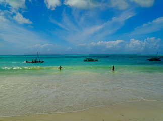 Glücklich am Strand auf Sansibar Jambiani im türkisen Wasser und Wolken am Himmel