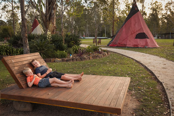 Two brothers relaxing on daybed at tipi camp ground © Caseyjadew