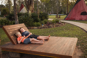 Two brothers relaxing on daybed at tipi camp ground © Caseyjadew