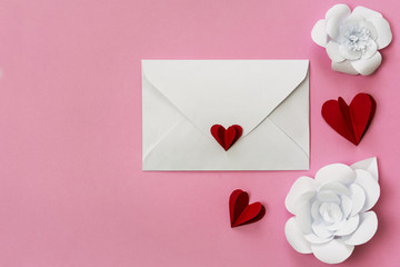 Valentine's Day flat lay with love letter envelope, red paper hearts and white flowers, copy space on left side.