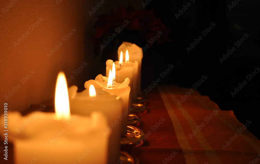 Wall mural rows of burning candles in a dim room during christmas time