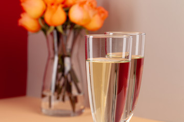 Close up photo of champagne glasses with roses in a vase