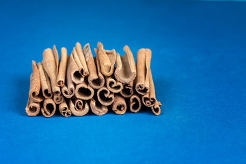 bunch of cinnamon sticks on blue background, empty space for text, ingredient for cooking
