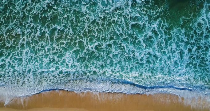 Aerial slow motion view of the waves breaking at the beach in Comporta, Portugal
