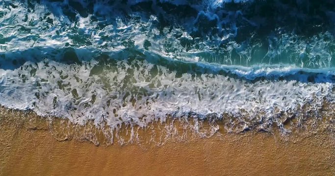 Aerial slow motion view of waves breaking at the beach in Comporta, Portugal