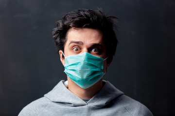 young white man in protective mask on dark background