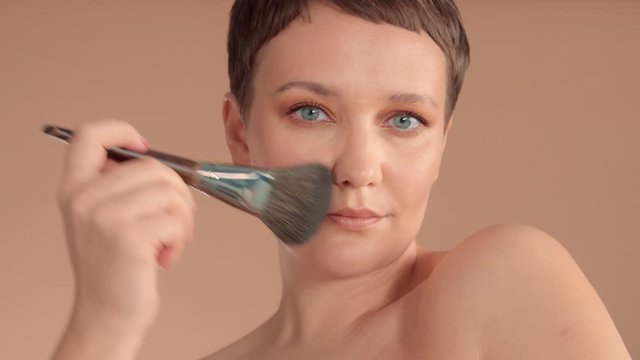closeup caucasian woman does her makeup using a fluffy makeup brush