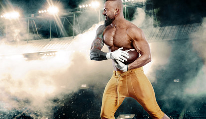 American football player. Sportsman with ball on stadium in action. Sport wallpaper. Team sports.