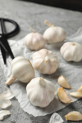 Garlic bulbs, slices, scissors, rosemary on grey background, closeup