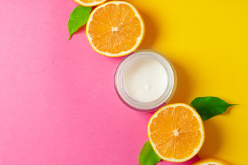 Cosmetic bottle with sliced citrus fruits on bright pink background