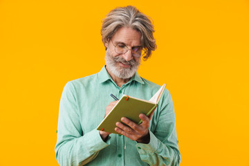 Bearded man in blue shirt writing notes in notebook.