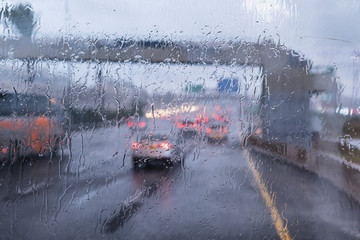 Traffic during rain on the highway, view through the windshield and focus on raindrops. Horizontal...