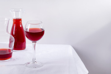 red wine in a wineglass, decanter and bottle with shadows isolated on white textile background