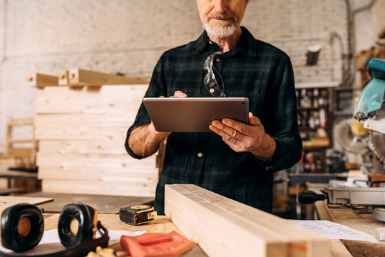 Cropped shot of a senior carpenter looking at digital tablet in his workshop - Powered by Adobe