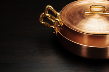 Fototapeta na wymiar Shiny vintage copper cookware over dark background