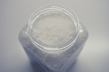 White sea salt in a plastic container close-up.