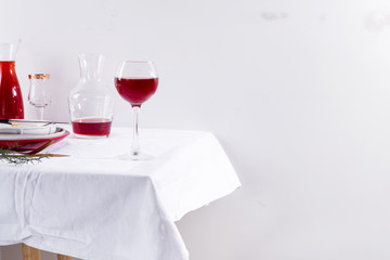 red wine in a wineglass, decanter and table setting with shadows isolated on white textile background