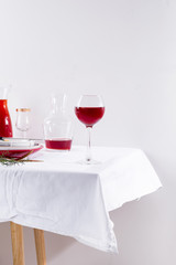 red wine in a wineglass, decanter and table setting with shadows isolated on white textile background
