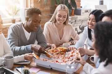 Happy multiracial colleagues eating pizza in office