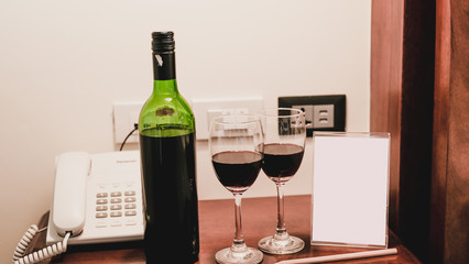 Two glasses of wine and wine bottle with phone on the wooden table