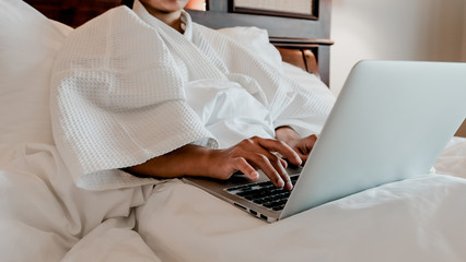 Naklejka premium Picture of tourists businesswoman hands work with laptop on a bed in the luxury hotel room, healthy food concept. 