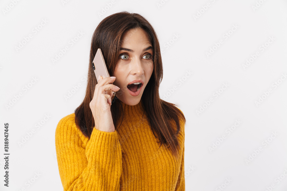 Wall mural Image of beautiful brunette adult woman wondering and talking on cellphone