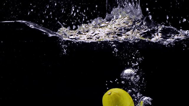 Lemon falls in the water in slow motion. Isolated on black background. Close up view. Shot with cinema camera RED Dragon, UHD, 240fps.