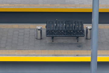 Empty bench on the platform without people. The empty platform with seats at the railway station.