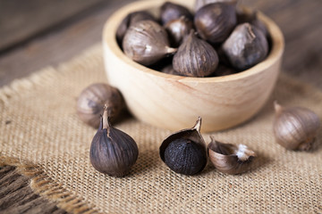 Black garlic on sack cloth and wooden table - 318948848