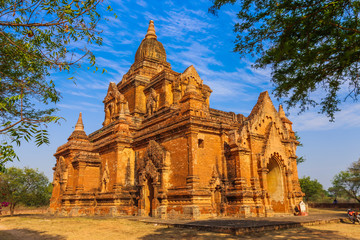 Ancient pagoda against the blue sky and trees in Bagan, Myanmar