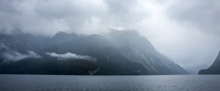 Clouds and fog at Doubtfull Sound. Fjordland New Zealand. South Island. Mysterious. Panorama. Grey landscape. Coast. Grey clouds. Rain. Moist.