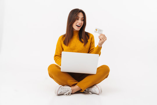 Image of brunette adult woman holding laptop computer and credit card