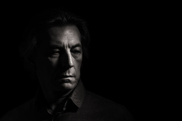 Portrait of a stern man on a black background with space for text. - obrazy, fototapety, plakaty