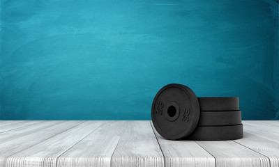3d rendering of black weight plates on white wooden floor and dark turquoise background