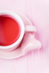 Fruit red tea and pink ceramic heart on pale pink background, copy space