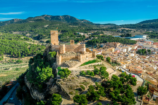 Aerial view of Biar castle in Valencia province Spain with donjon towering over the town and concentric walls reinforced with semi circular towers on a sunny day with blue sky