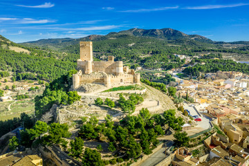 Obraz premium Aerial view of Biar castle in Valencia province Spain with donjon towering over the town and concentric walls reinforced with semi circular towers on a sunny day with blue sky