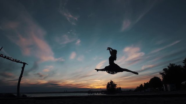 ballerina makes high beautiful jumps. silhouette of a ballerina against the sunset sky